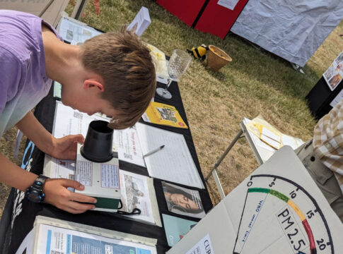 What am I breathing? A young visitor to Ealing Friends of the Earth’s stall, takes a reading from the PM2.5 meter. Photo: Ealing Friends of the Earth